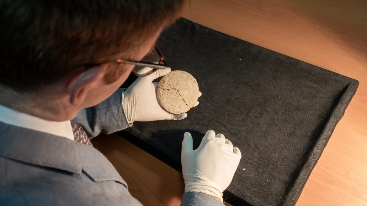 Dr Mansfield's gloved hands hold the disc-shaped tablet, about 20cm across, which is cracked and has markings on the flat sides
